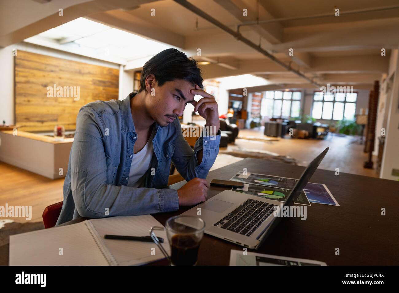 Jeune homme travaillant à la maison sur son ordinateur portable Banque D'Images