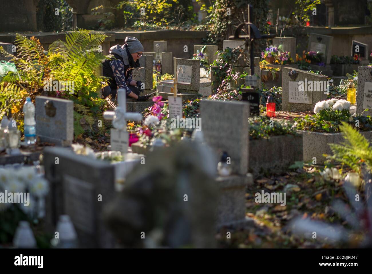 Une femme prend une photo avec son téléphone portable d'une tombe dans le cimetière de Rakowicki à Cracovie, Pologne 2019. Banque D'Images