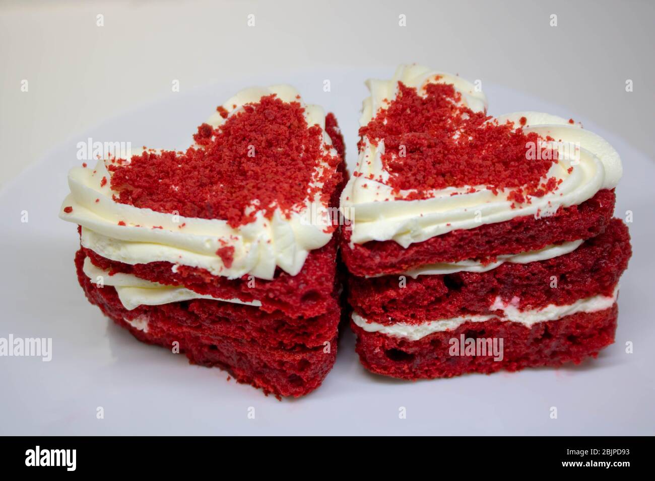 Carte de Saint-Valentin, fête des mères, 8 mars. Biscuits sucrés avec une crème et un coeur rouge sur fond blanc. Dessert Banque D'Images