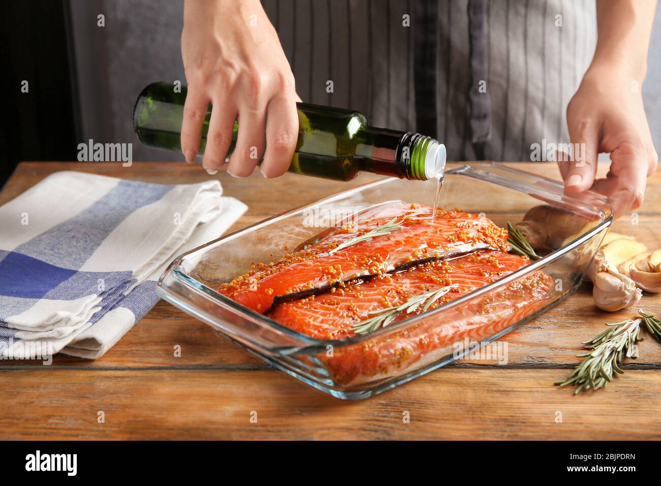 Femme préparant un filet de saumon avec marinade dans un plat de cuisson Banque D'Images