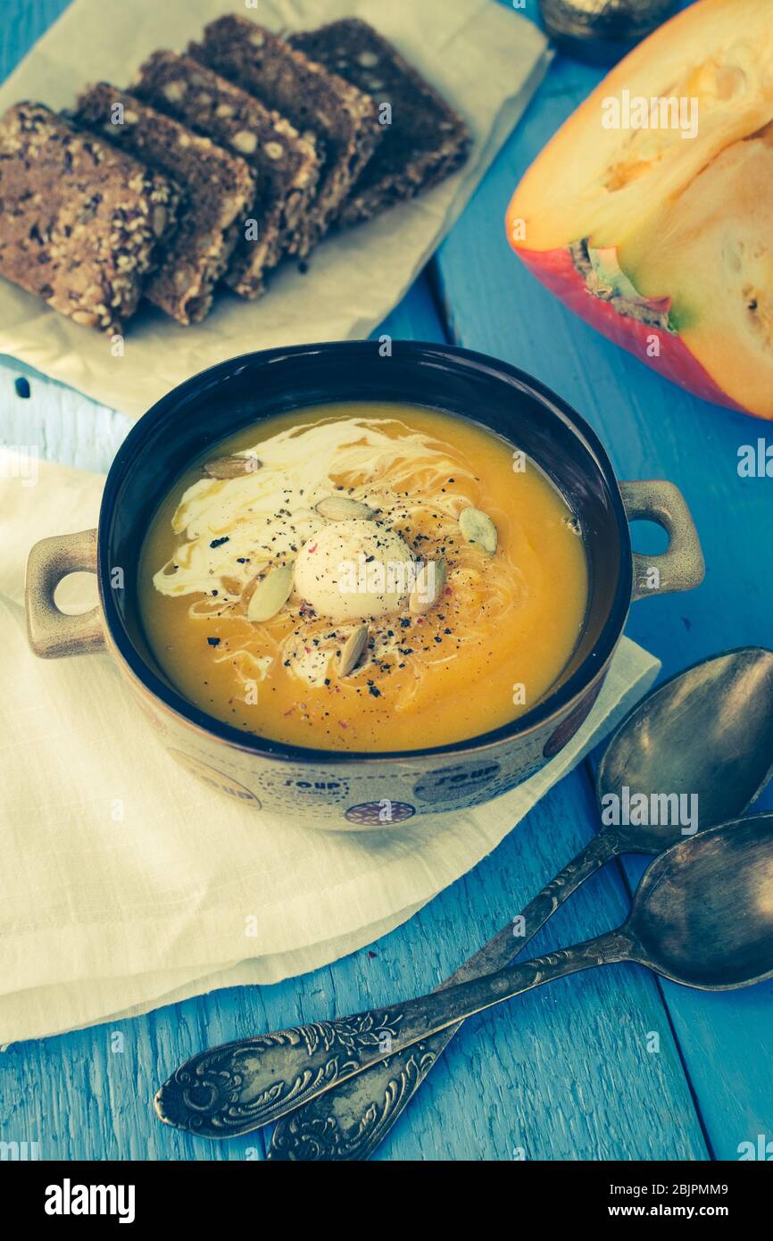 Soupe de citrouille avec crème, fromage et graines de citrouille sur fond bleu en bois. Soupe de citrouille aux citrouilles fraîches. Halloween Thanksgiving cuisine d'automne conc Banque D'Images