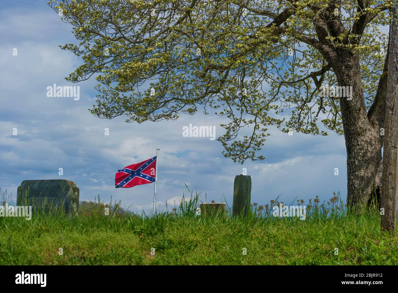 Elizabethton, Tennessee, États-Unis - - 5 avril 2020: Un vieux cimetière sur une colline sous ciel nuageux avec un drapeau confédéré voler et un printemps florissant tr Banque D'Images