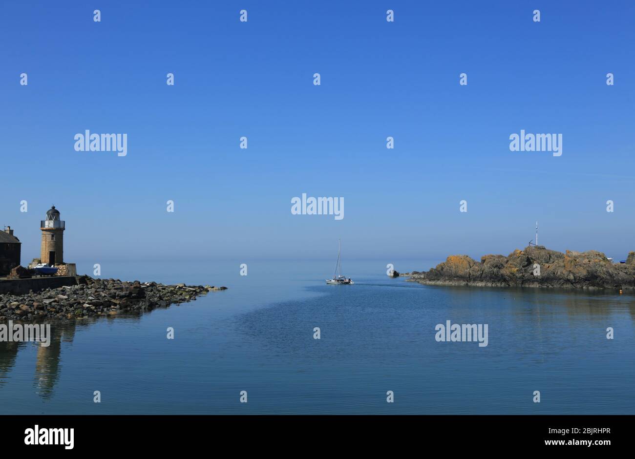 Un petit bateau quitte le port de Portpatrick par une journée calme et ensoleillée. Banque D'Images