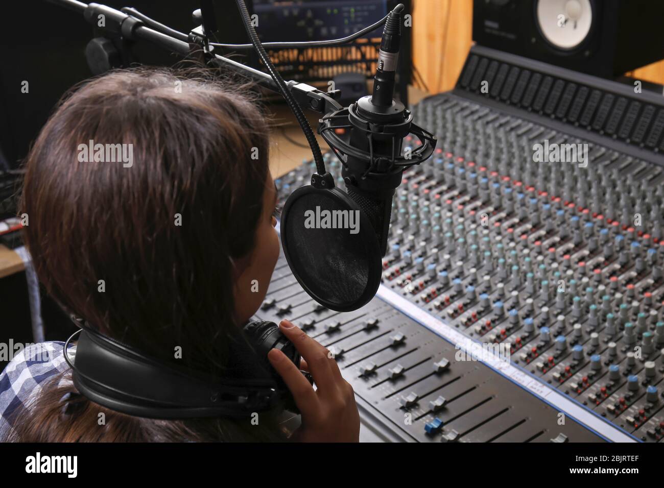 La radio hôte féminine diffuse par microphone en studio Banque D'Images