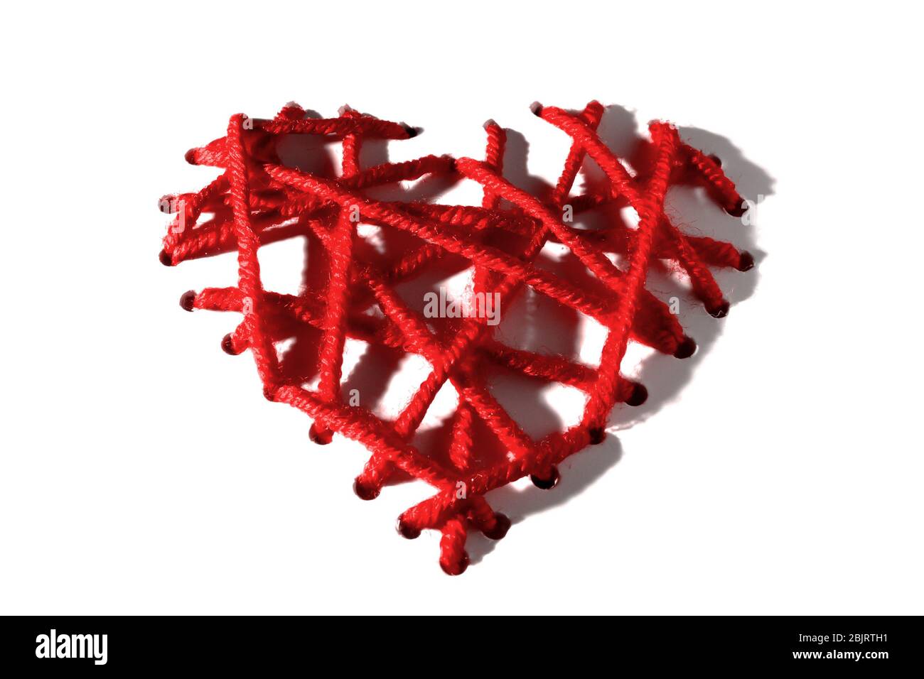 Coeur de broderies rouges avec ombres dures pour la Saint-Valentin sur fond blanc. Isoler Banque D'Images