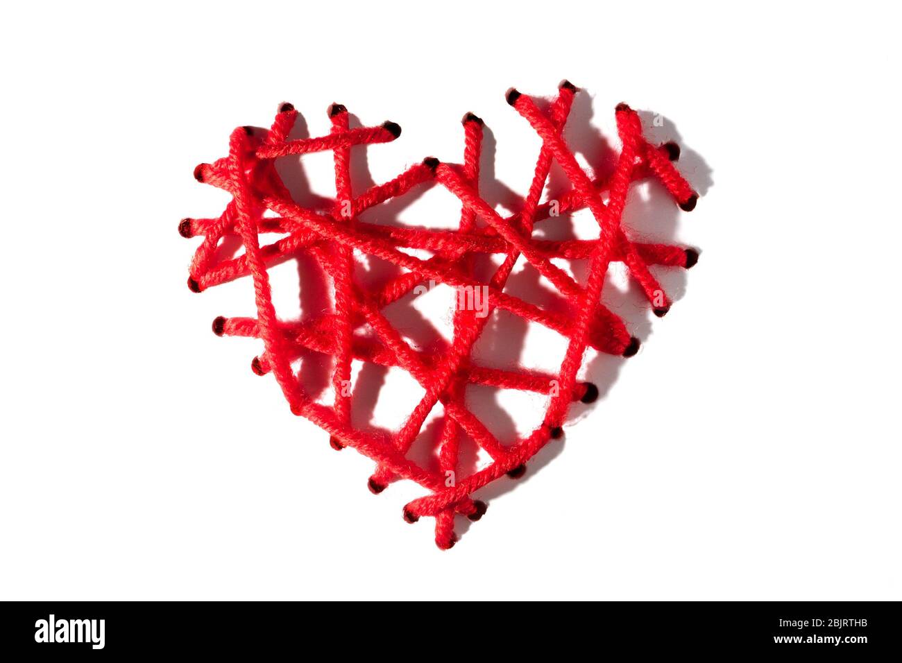 Coeur de broderies rouges avec ombres dures pour la Saint-Valentin sur fond blanc. Isoler Banque D'Images