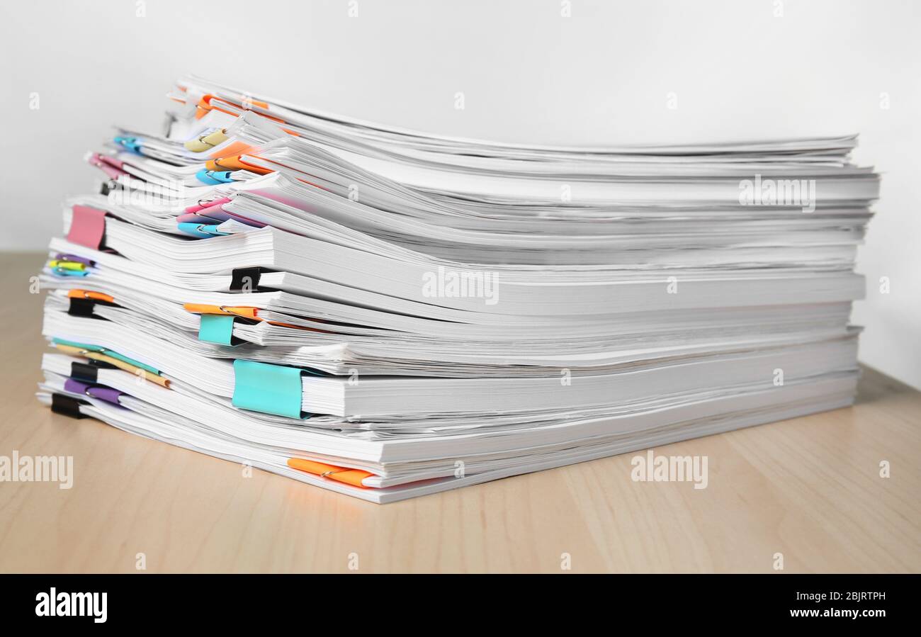 Pile de documents sur la table contre fond blanc Banque D'Images
