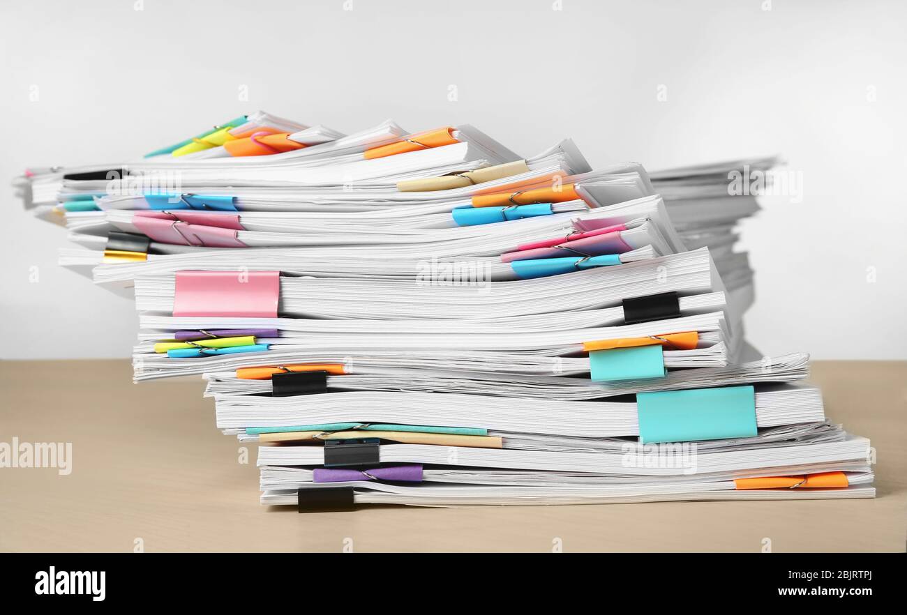 Pile de documents sur la table contre fond blanc Banque D'Images
