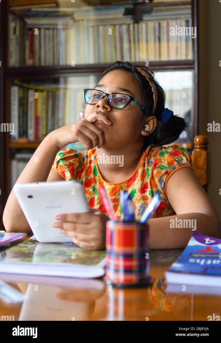 Jolie petite fille indienne étudiant à la maison pendant la période de verrouillage en raison de la pandémie du virus Corona Banque D'Images