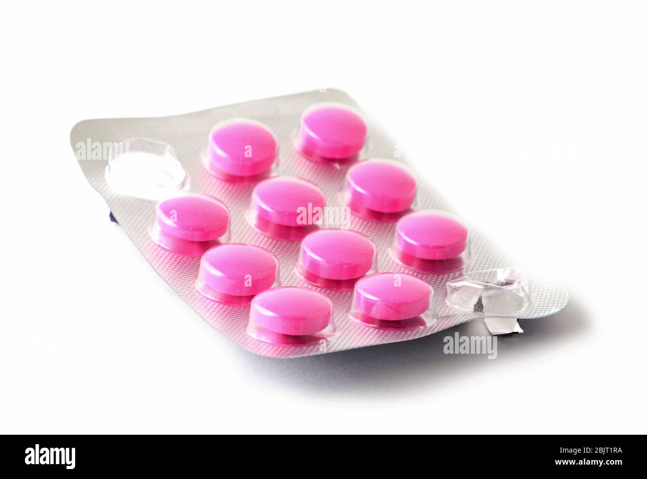 Macro-shot de l'emballage entier de blister avec des pilules roses et quelques comprimés manquants comprimés pressés sur fond blanc. Banque D'Images