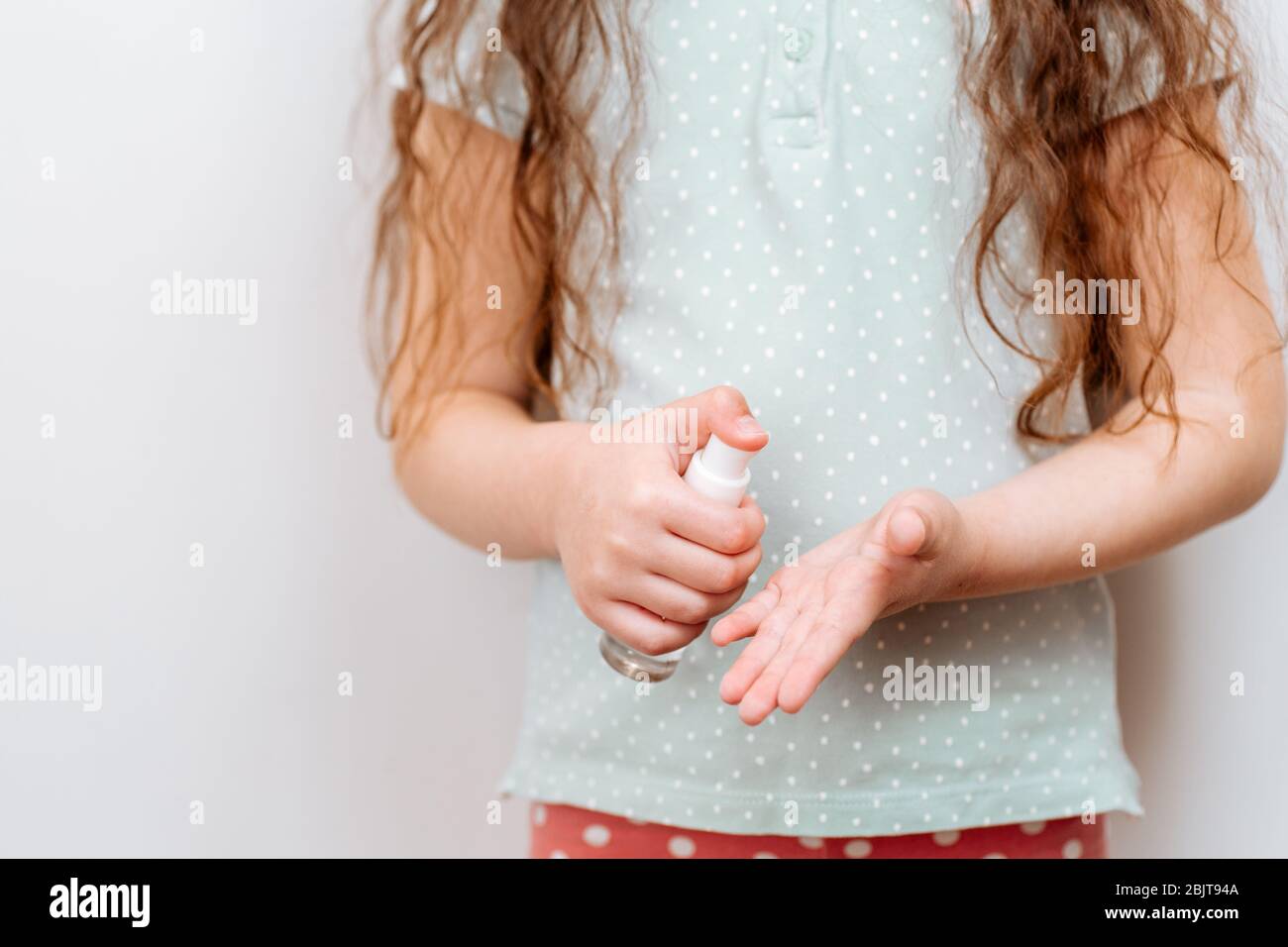 L'enfant utilise un gel antiseptique antibactérien pour désinfecter les mains des bactéries. Banque D'Images