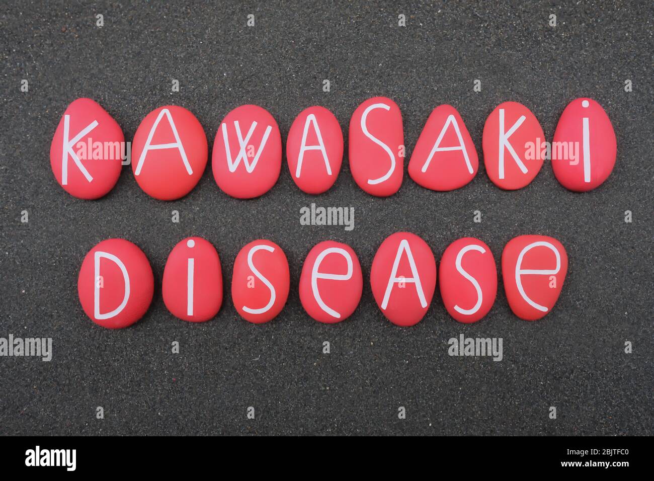 Maladie de Kawasaki, nom de maladie composé de lettres en pierre de couleur rouge sur le sable volcanique noir Banque D'Images