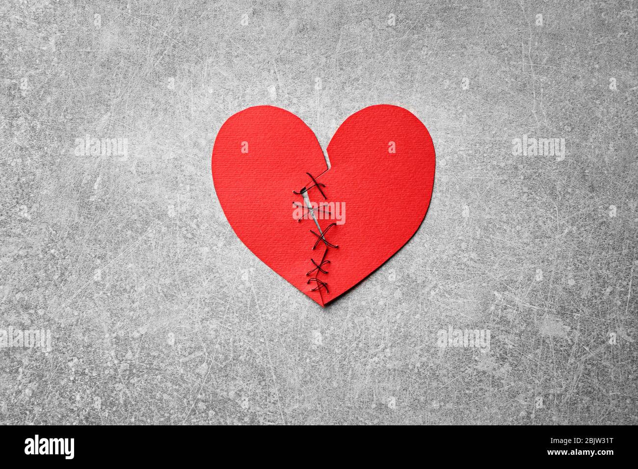 Coeur en papier coupé en deux et cousu ensemble sur fond clair. Problèmes de relation Banque D'Images