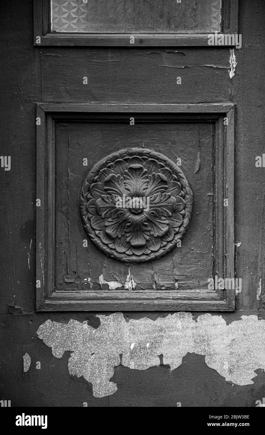 Photo en noir et blanc de l'élément de travail architectural de l'ancienne porte en bois avec peinture écaillée. Rosette sculpturale dans le cadre carré du panneau de porte de cla Banque D'Images
