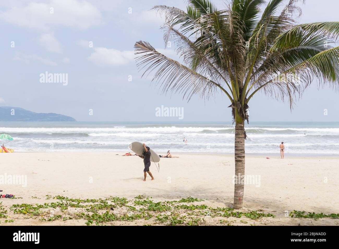 Vietnam Beach - UN surfeur qui marche le long de My Khe Beach à Da Nang au Vietnam, en Asie du Sud-est. Banque D'Images