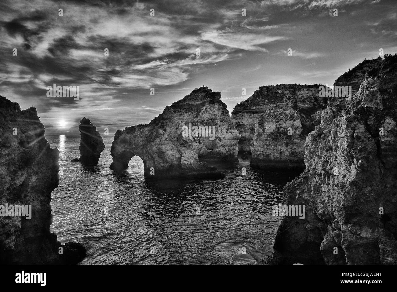 Le soleil se lève parmi les formations rocheuses le long de la côte sud du Portugal dans la ville de Lagos. Banque D'Images