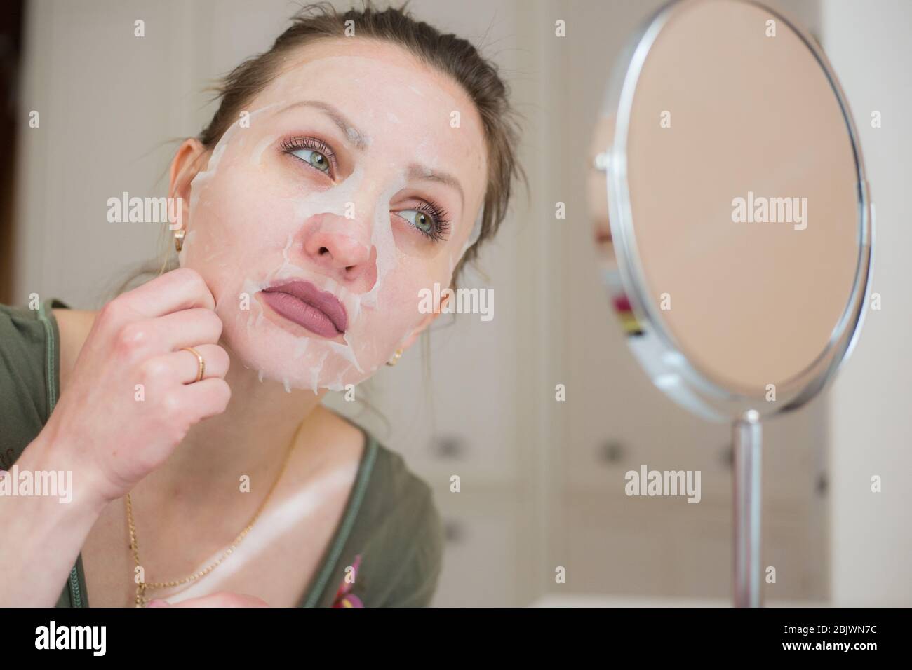 Masque cosmétique et fille regarder dans le miroir Banque D'Images