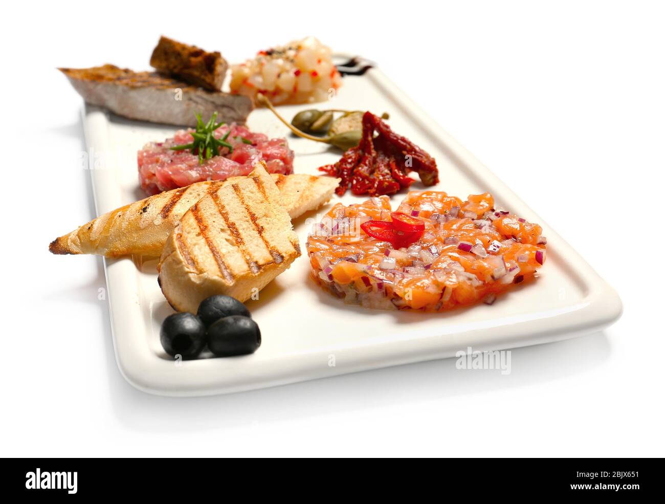 Assiette avec délicieux tartars de poisson et en-cas sur fond blanc Banque D'Images