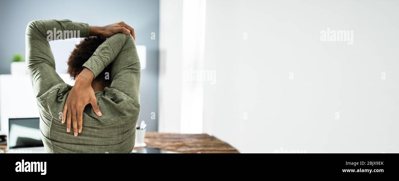 Employé s'étendant au bureau au travail Banque D'Images