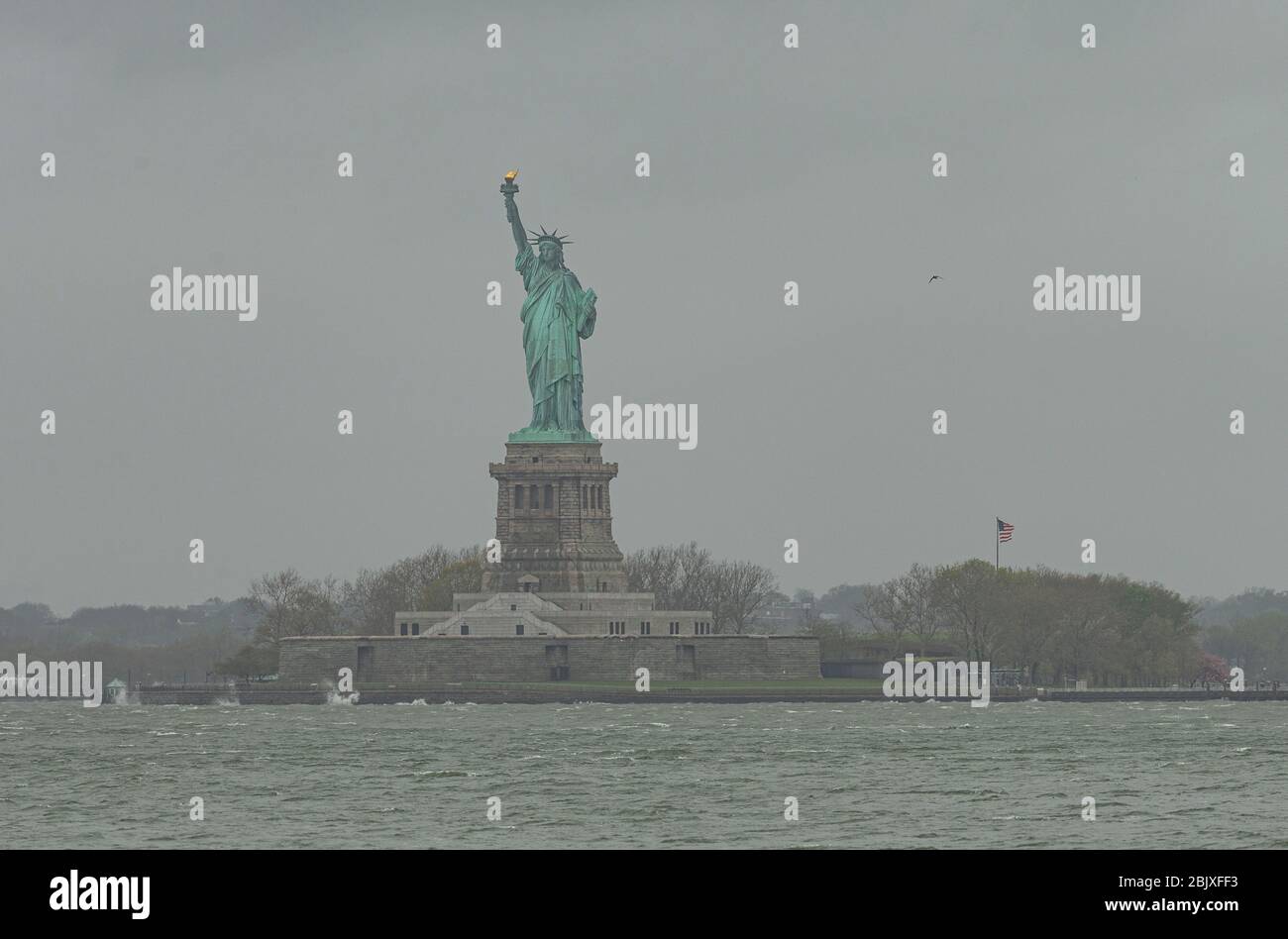 New York, NY - 30 avril 2020: Statue de la liberté vu dans le sombre jour de pluie quand USNS Comfort hôpital navire quitte après avoir traité certains patients pendant la pandémie COVID-19 Banque D'Images