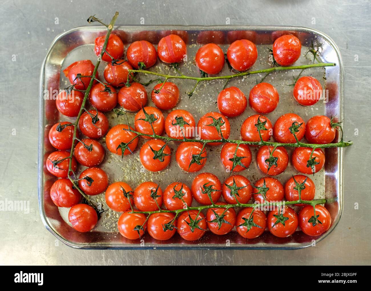 Tomates cerises cuites au four sur une plaque de cuisson dans la cuisine du restaurant. Vue de dessus, plan d'appartement Banque D'Images