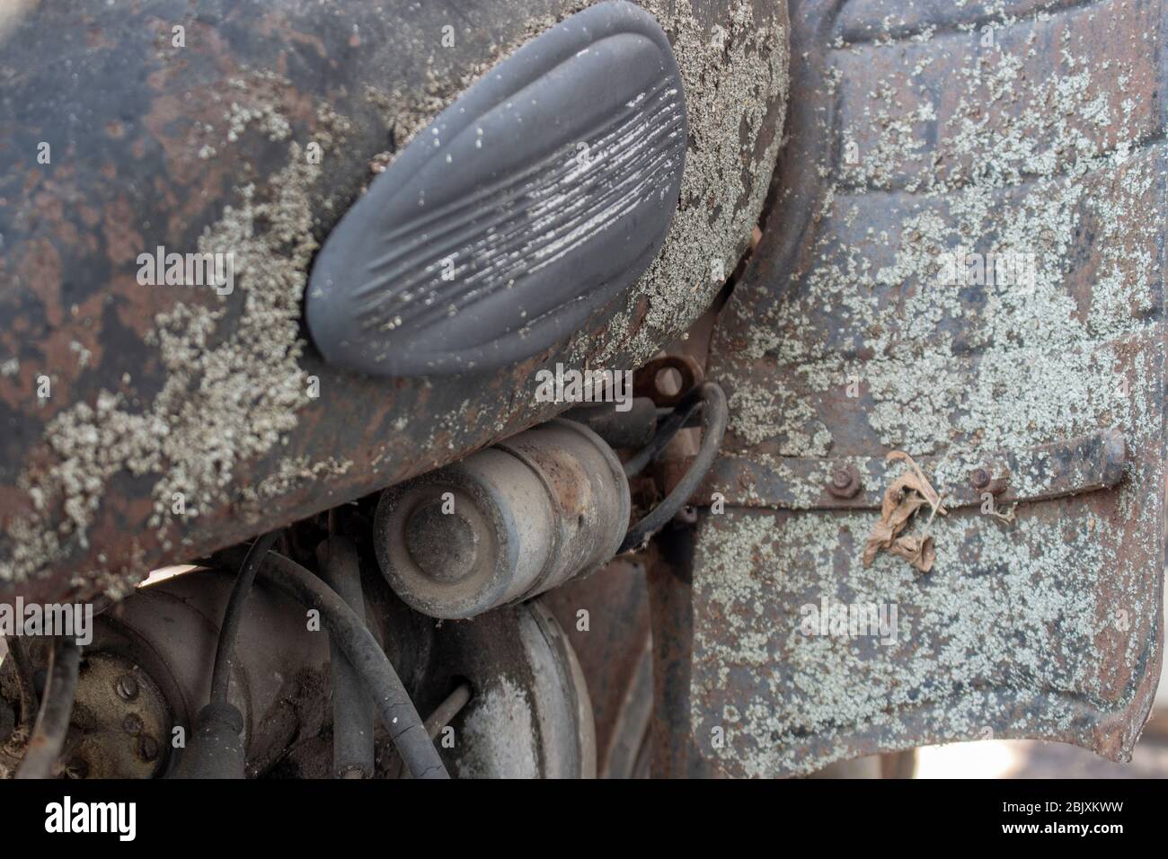 Partie du moteur et du réservoir d'un ancien vélo rétro recouvert de rouille et de saleté et de mousse. Banque D'Images