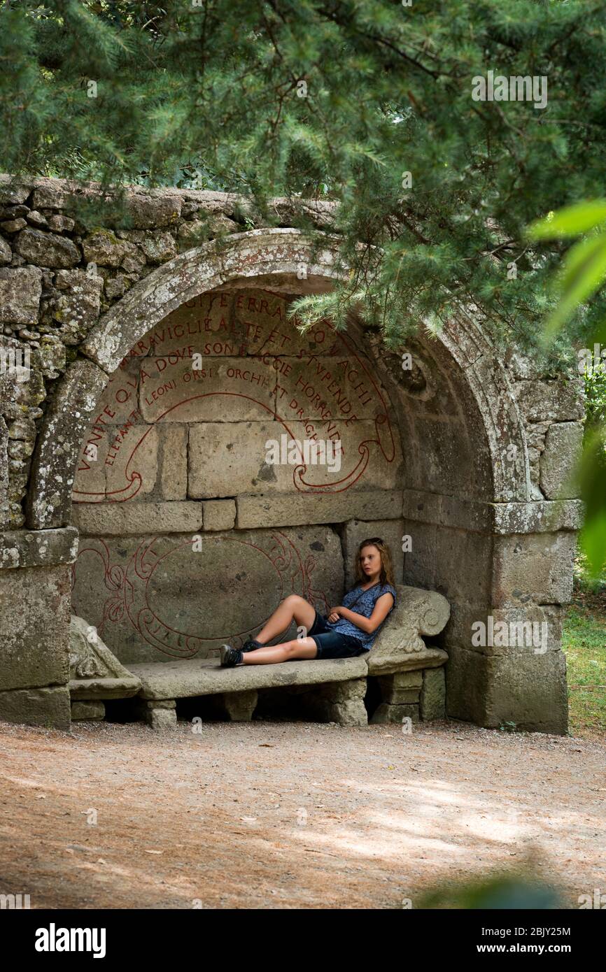 Une adolescente s'inclinait sur un banc en pierre à l'intérieur d'une niche archae à Monster Park, Parco dei Mostri, qui a été commandée en 1552 par Prince Pier Frances Banque D'Images