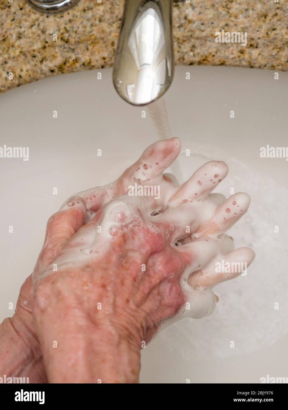 Femme âgée se lavant les mains dans le lavabo de la salle de bains, gros plan des mains Banque D'Images