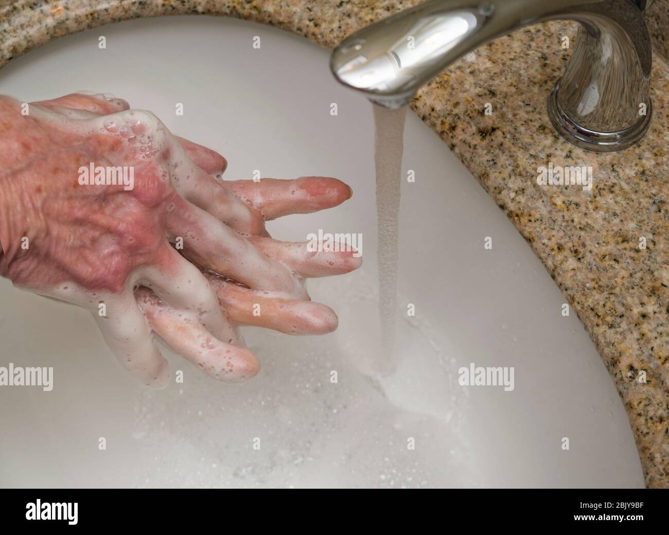 Femme sénior se lavant les mains dans le lavabo de la salle de bains, les mains se ferment Banque D'Images