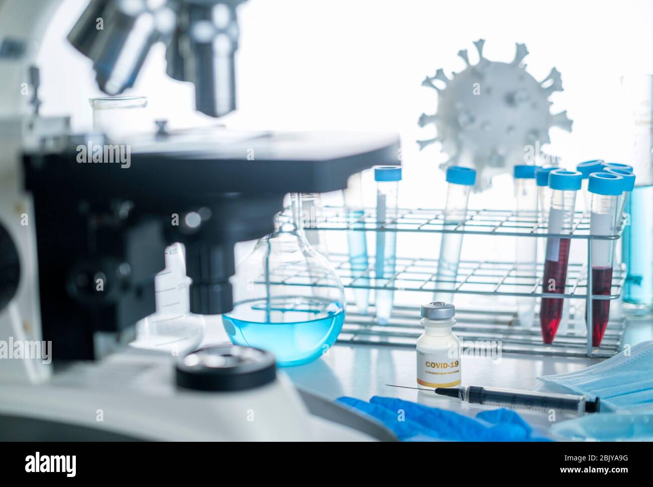 Microscope en laboratoire avec modèle de coronavirus, flacons et vaccin Banque D'Images