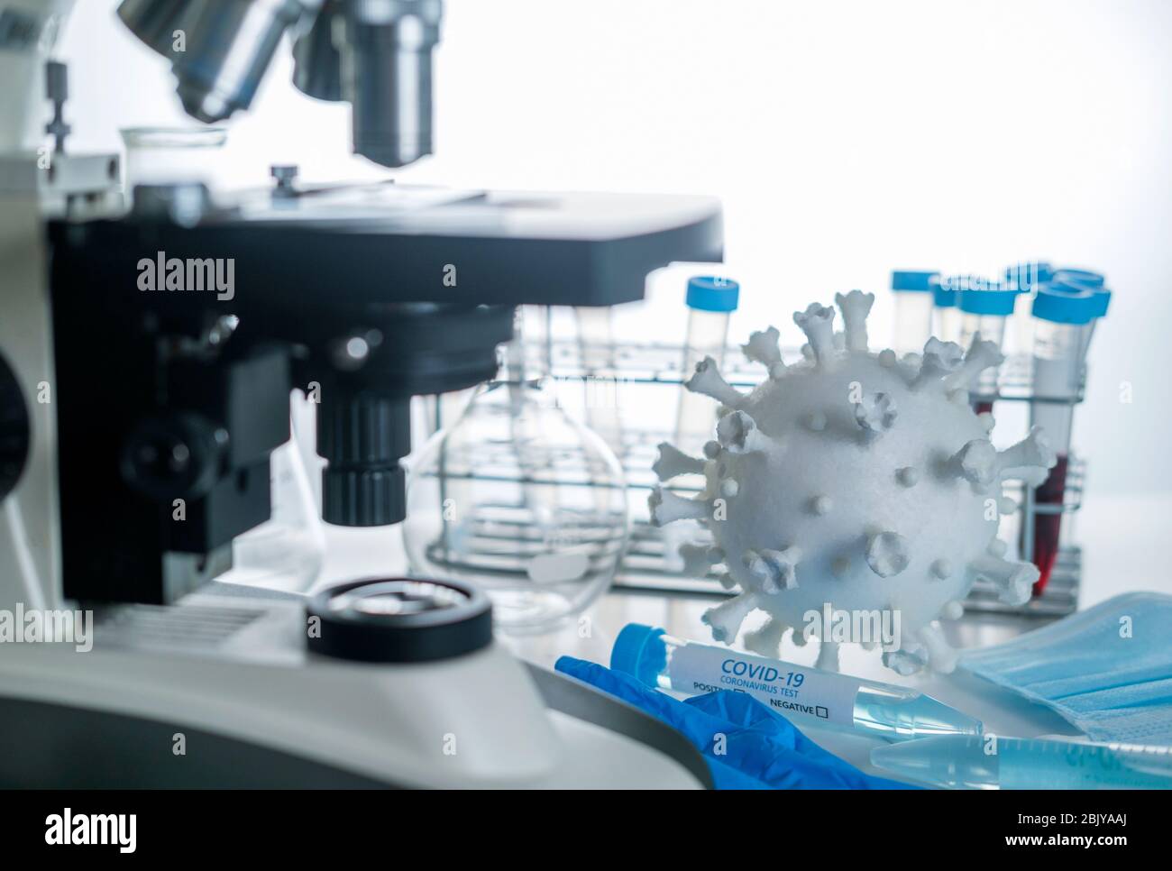 Microscope en laboratoire avec modèle de coronavirus et flacons d'essai Banque D'Images