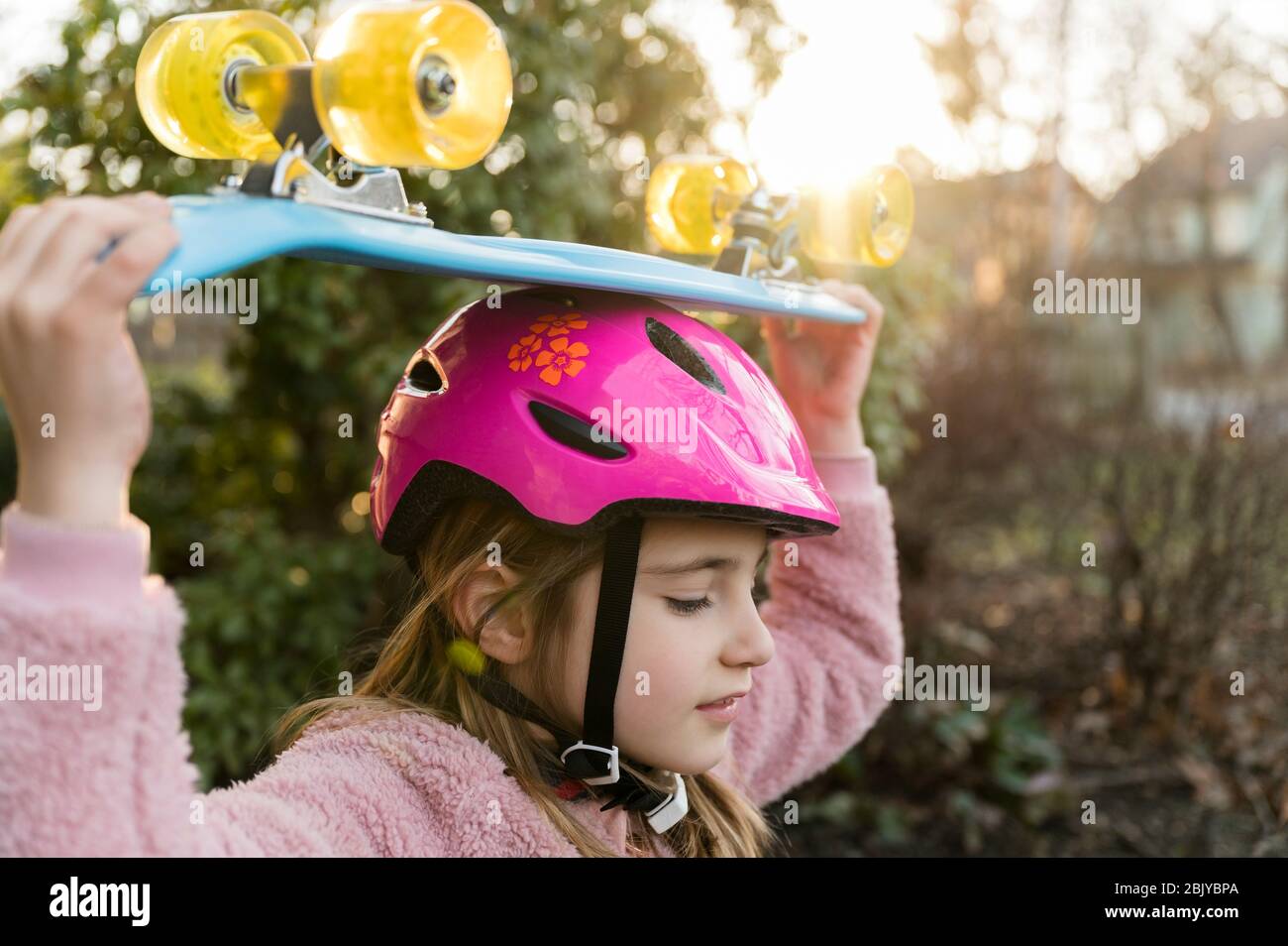 Fille portant une planche à roulettes sur la tête Banque D'Images