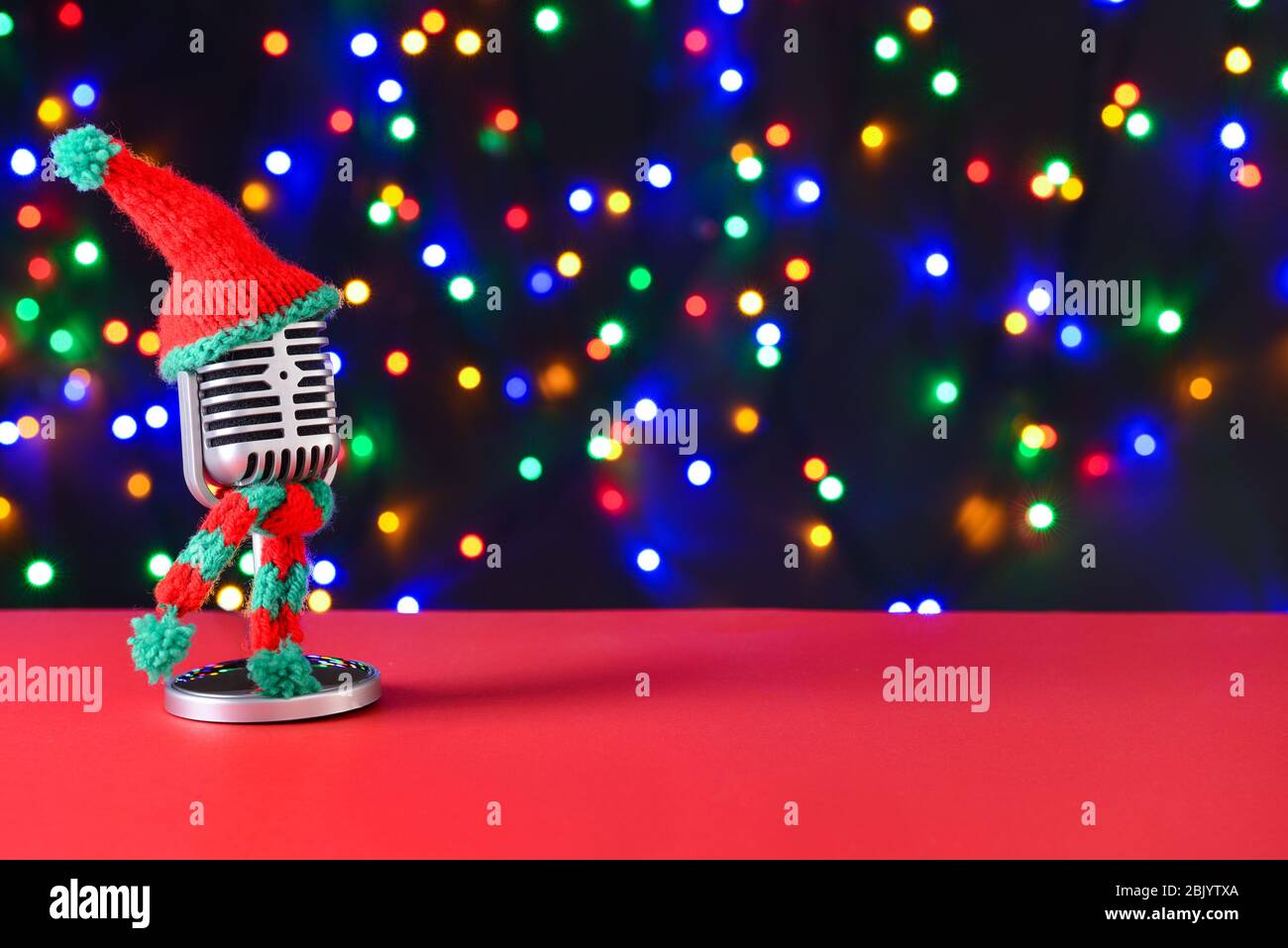 Microphone rétro avec bonnet et écharpe en tricot sur la table contre les feux de flou artistique Banque D'Images