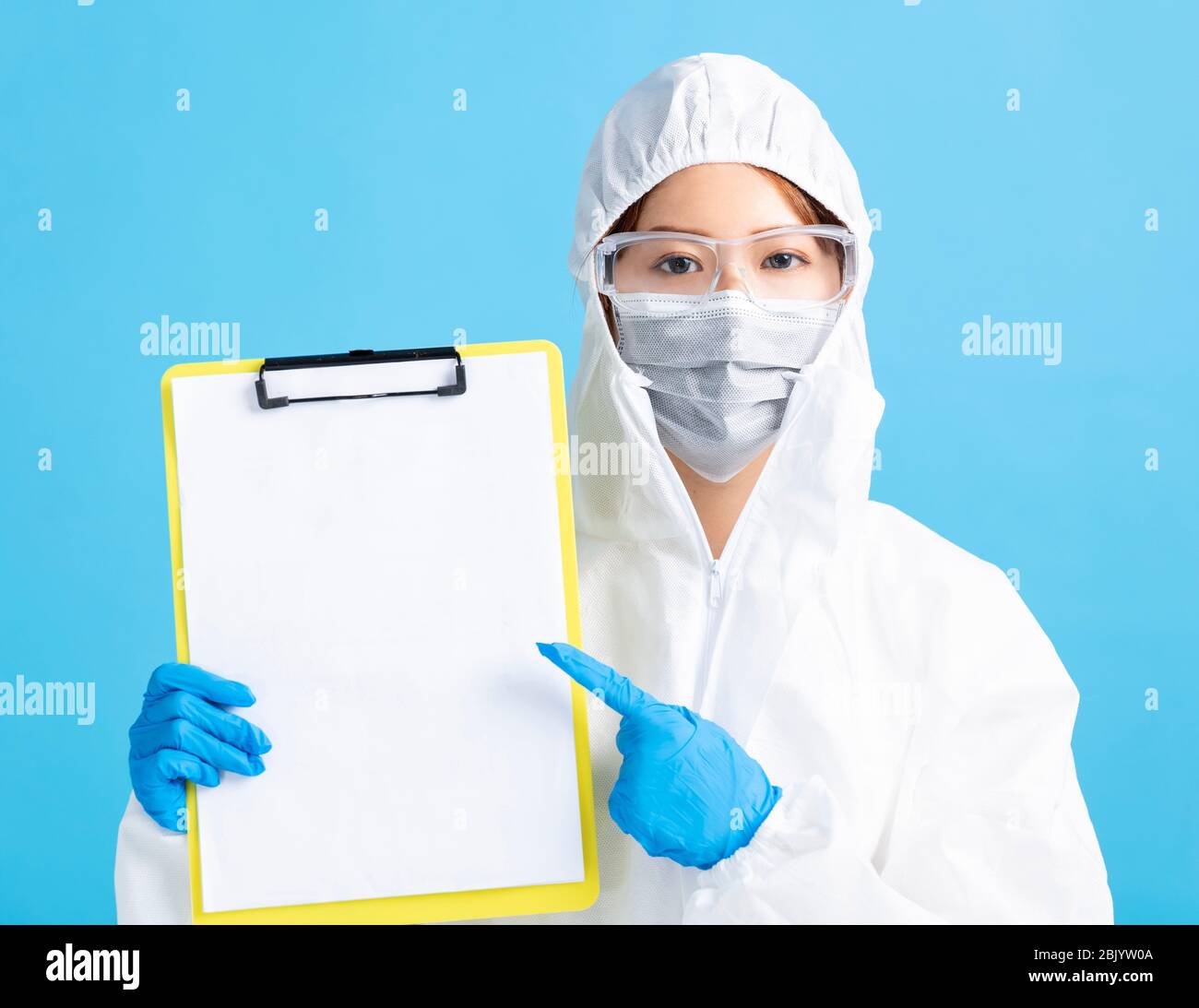 infirmière féminine portant un masque médical avec lunettes de sécurité et une combinaison de protection blanche. elle présente un rapport d'examen médical vierge. Banque D'Images
