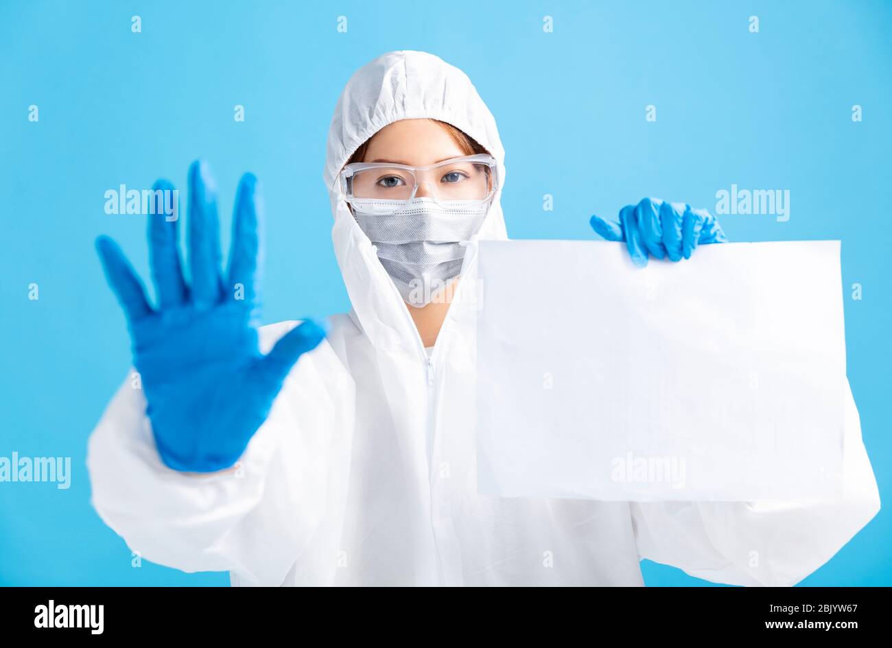infirmière féminine portant un masque médical avec lunettes de sécurité et un costume de protection blanc. montrant un panneau d'affichage vierge Banque D'Images