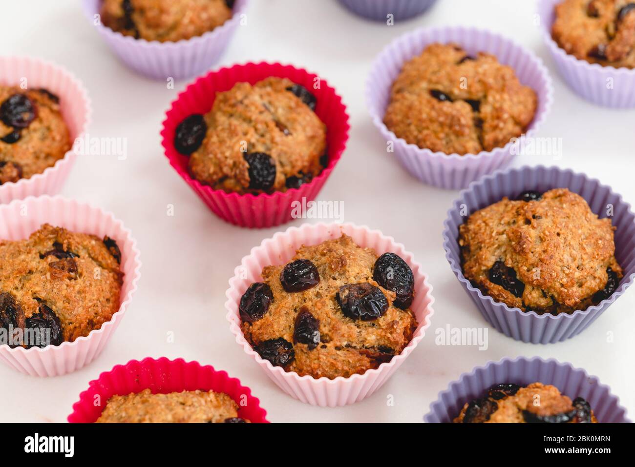 Muffins au son avec canneberges sèches se rapprochent dans des tasses en silicone sur fond blanc. Nourriture saine, bonne source de fibres alimentaires Banque D'Images