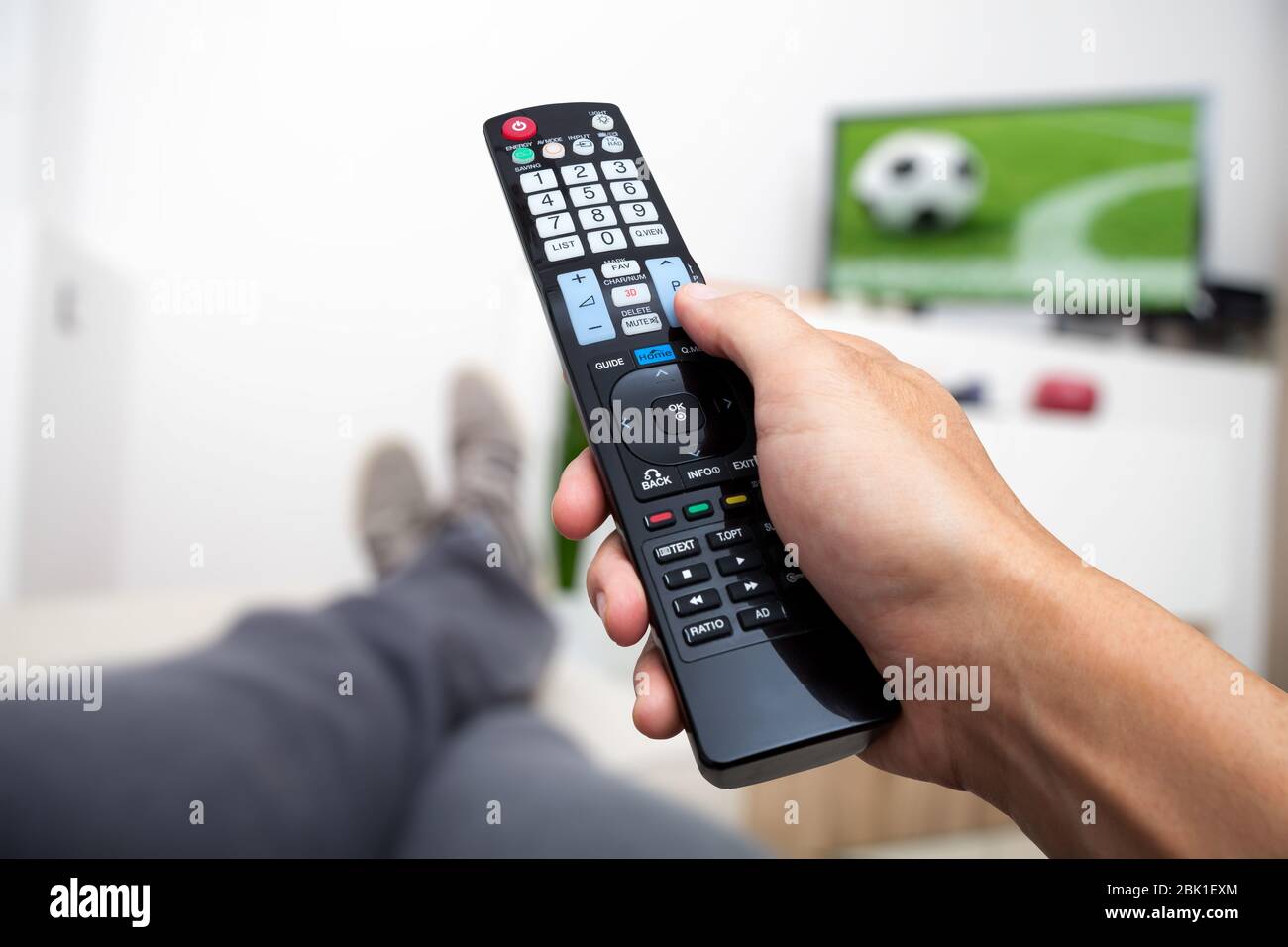 Regarder la télévision. La télécommande en main. Regarder le football à la télévision. L'homme allongé sur le canapé en regardant la télé Banque D'Images