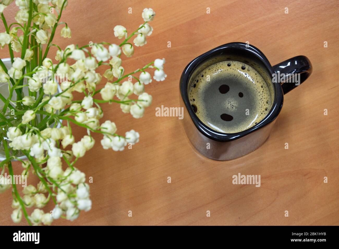 Grand angle de fleurs printanières (nénuphars de la vallée) et tasse à café sur table en bois Banque D'Images