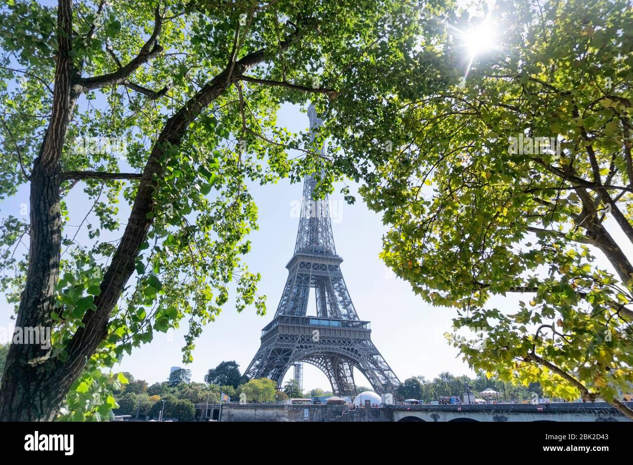 Vue sur la Tour Eiffel à Paris à travers les feuilles vertes des arbres à midi. Banque D'Images