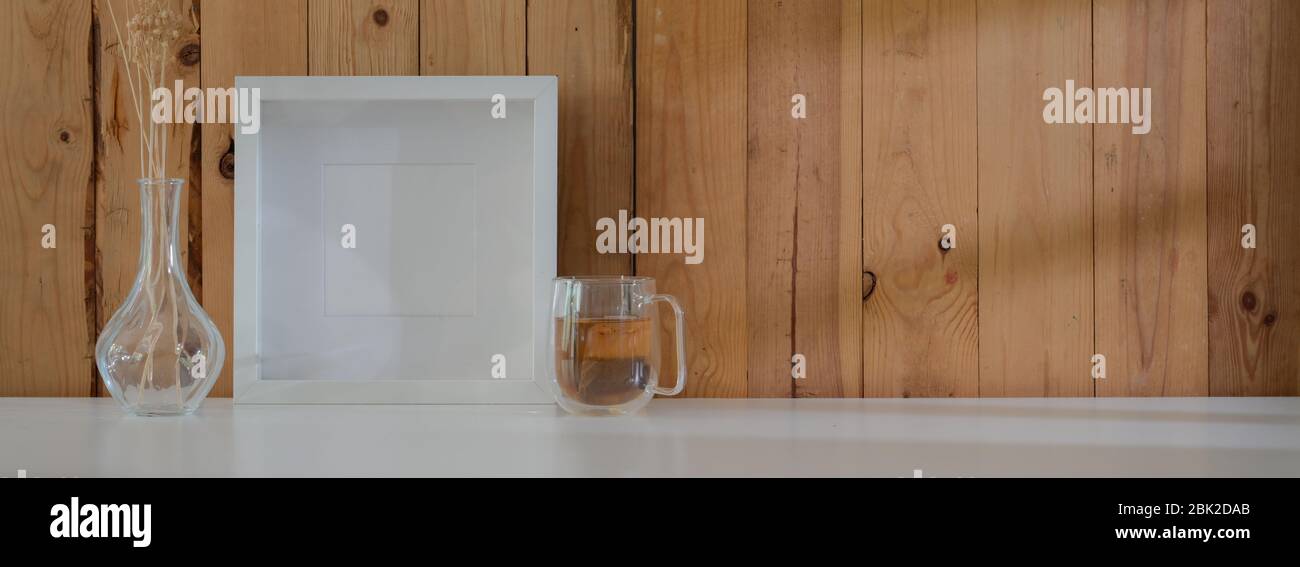 Vue rapprochée de l'espace de travail rustique moderne avec tasse à thé, décorations et espace de copie sur une table blanche avec mur de planche Banque D'Images