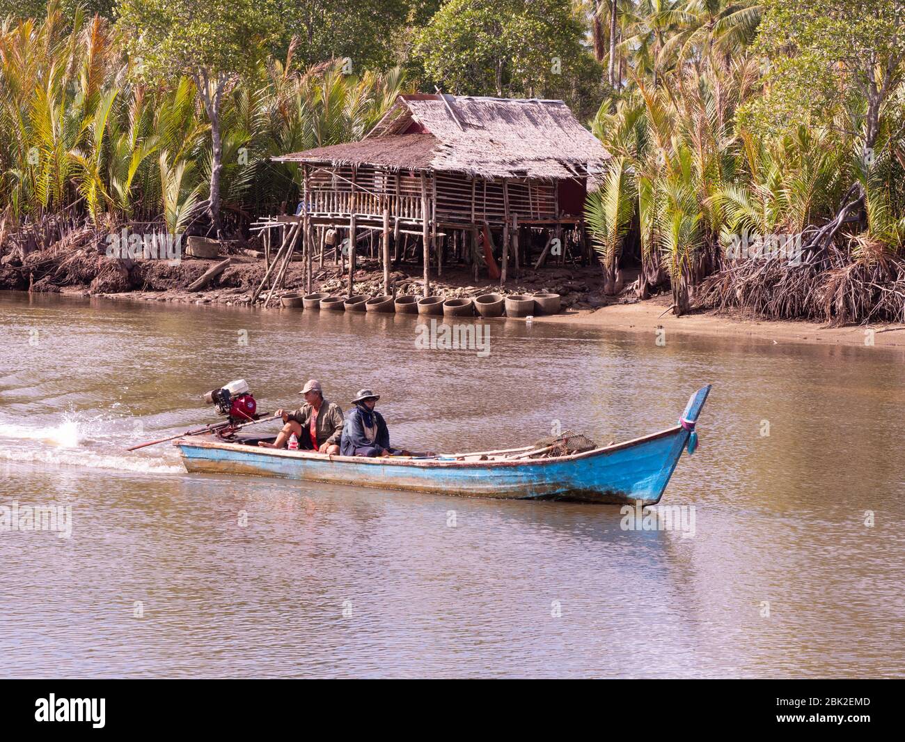 Petit bateau à queue longue sur Mak Bang, Satun City, Satun dans le sud de la Thaïlande. Maison traditionnelle sur pilotis en arrière-plan. Banque D'Images