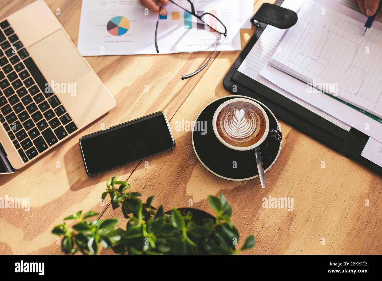 Vue sur la tasse de café d'art cappuccino chaud sur une table en bois avec des hommes d'affaires travaillant sur certains documents. Tasse de café avec mousse de lait art modèle o Banque D'Images