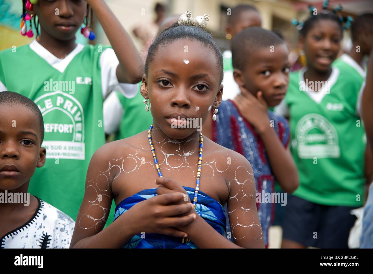 abidjan, côte ivoire - 13 février 2018 : portrait d'une petite fille avec un morceau de toile de cintre bleue attaché sur la poitrine portant un collier et avec un mak Banque D'Images