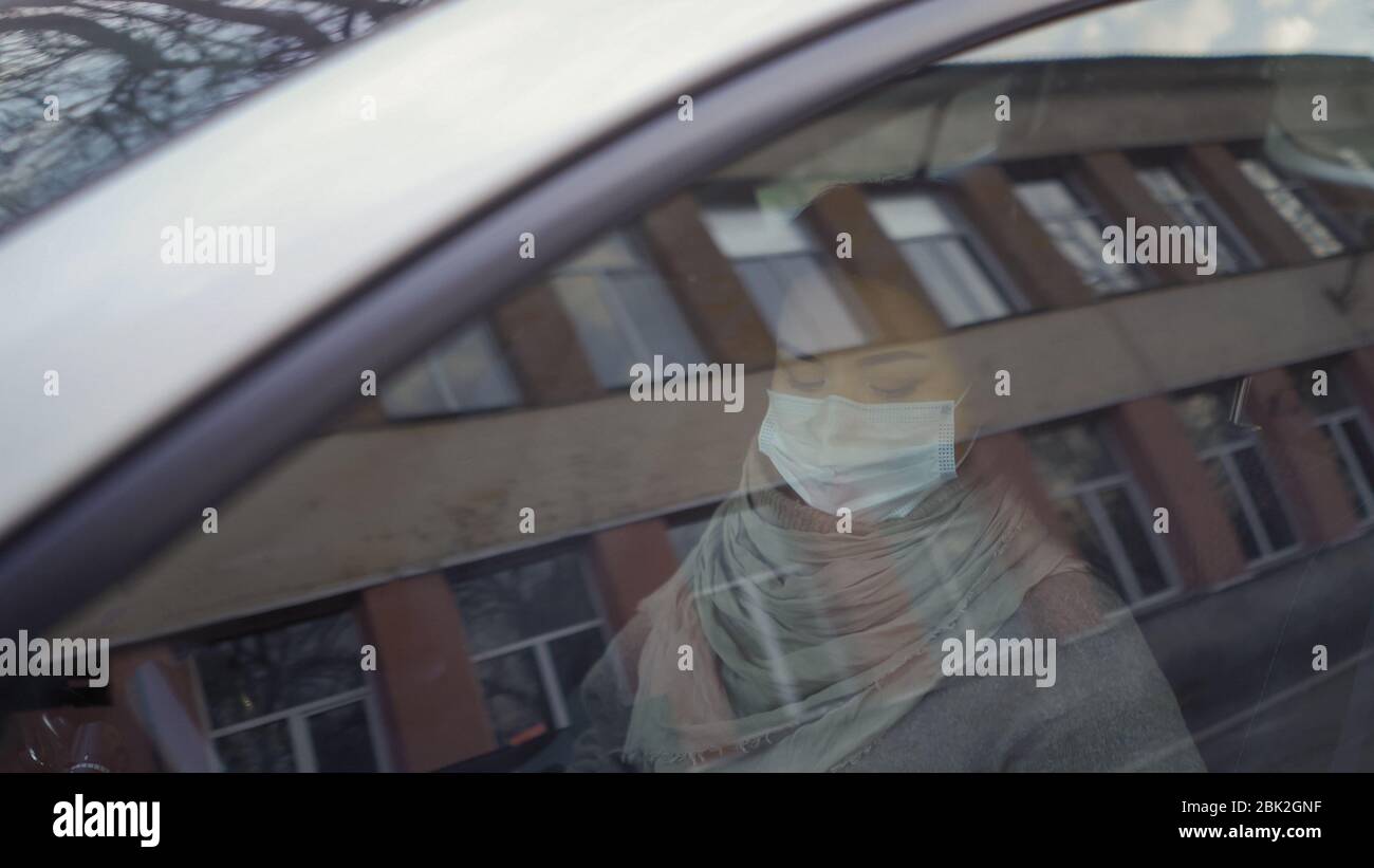 Femme assise en voiture portant un masque Banque D'Images