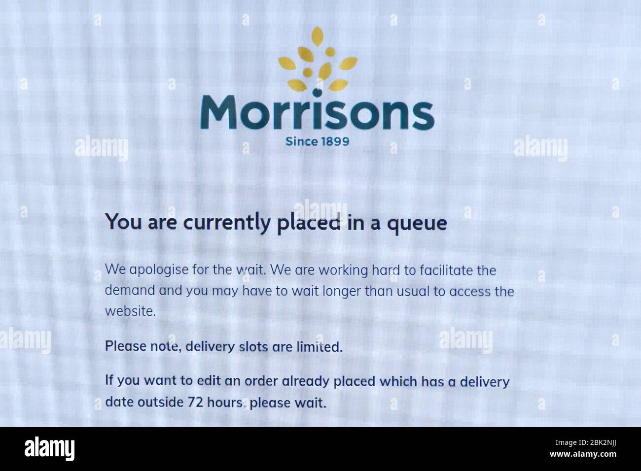 Morrisons supermarché site Web pour la commande en ligne d'aliments avec le message que vous êtes actuellement placé dans une file d'attente, pendant la pandémie de coronavirus, Royaume-Uni Banque D'Images