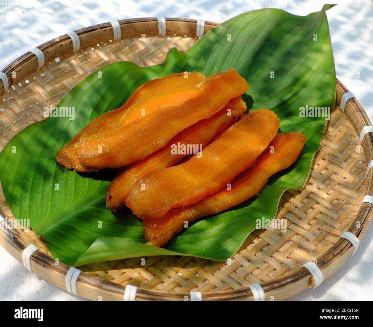 Plateau en bambou de nourriture maison pour le régime de snack, tranches de patate douce jaune qui séchée par exposition au soleil en jour chaud au Vietnam Banque D'Images