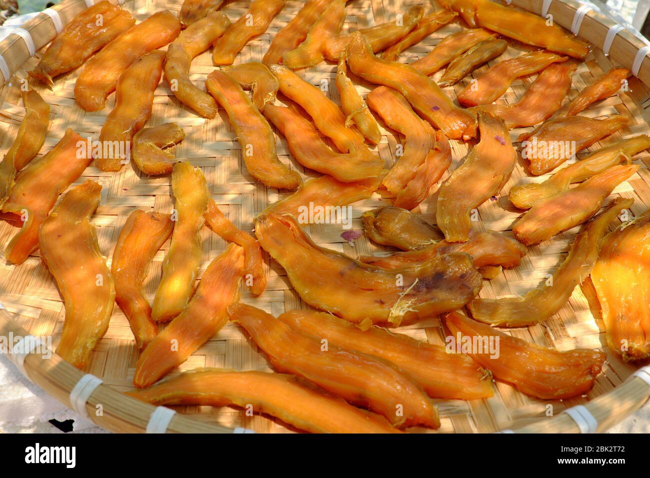 Plateau en bambou de nourriture maison pour le régime de snack, tranches de patate douce jaune qui séchée par exposition au soleil en jour chaud au Vietnam Banque D'Images