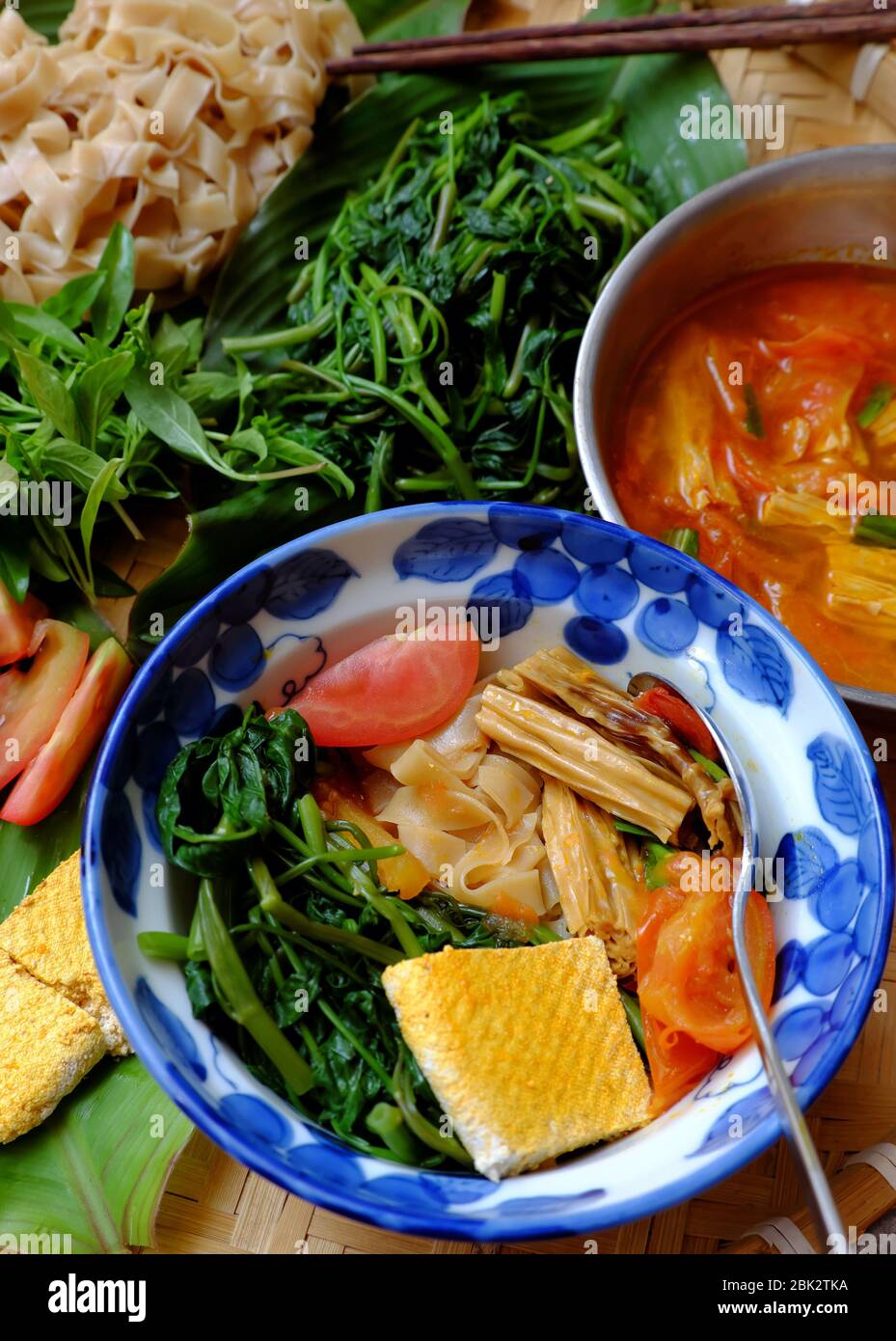 Plateau de nourriture petit déjeuner végétarien, soupe vietnamienne maison de nouilles de crêpes sèches, ingrédients eau épinards, tofu, tomate, riz sec nouilles, repas de végétalien Banque D'Images