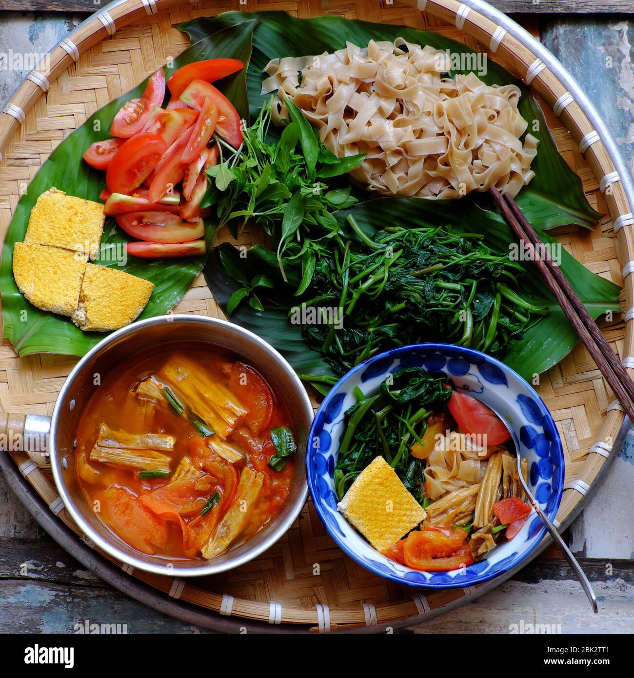 Plateau de nourriture petit déjeuner végétarien, soupe vietnamienne maison de nouilles de crêpes sèches, ingrédients eau épinards, tofu, tomate, riz sec nouilles, repas de végétalien Banque D'Images