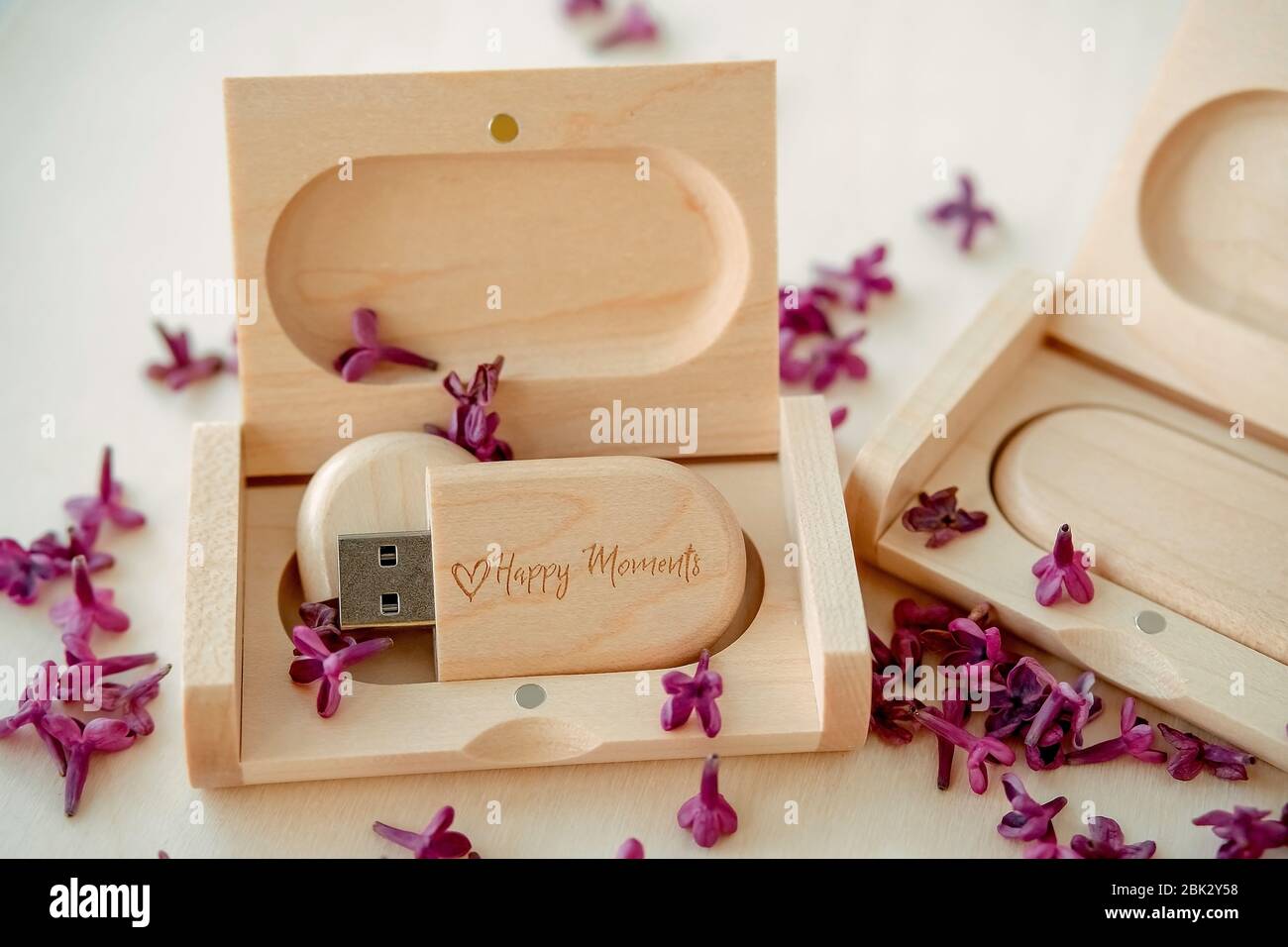 Clés USB marron en bois avec boîtes contenant le texte Happy moments avec pétales lilas sur fond blanc, stockage de données, belle rétroaction à clié Banque D'Images